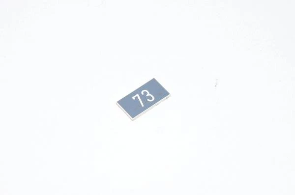Merkkikilpi, harmaa, 20x11mm suorakulmainen, "73"