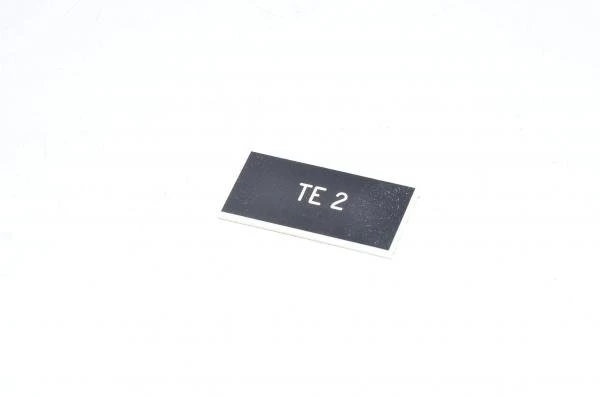 Merkkikilpi, musta, 37x19mm suorakulmainen, "TE 2"