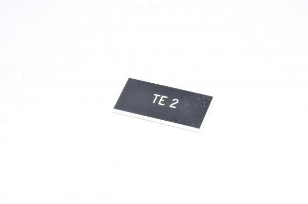 Merkkikilpi, musta, 37x19mm suorakulmainen, "TE 2"